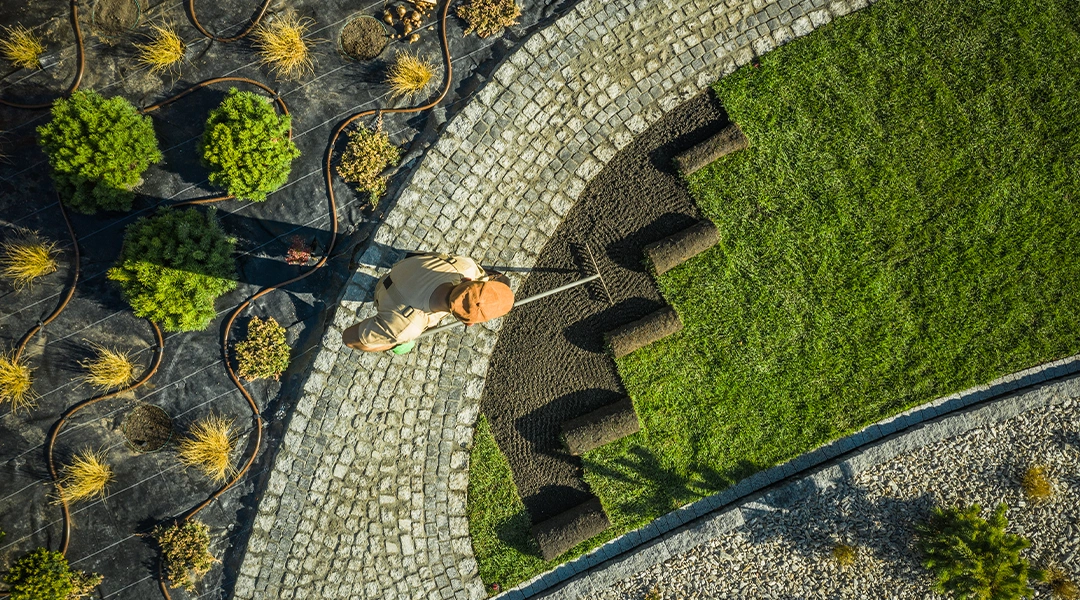 A landscape specialist is raking soil in preparation to lay new grass sod